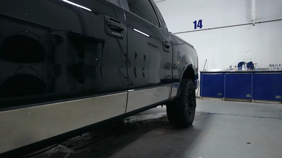 The same Ford F-150 side panel after detailing, washed and waxed to a mirror shine