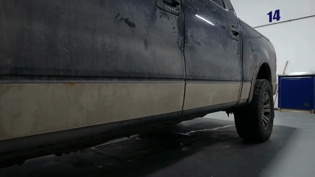 The dusty, road-filmed side of a black Ford F-150 before detailing at Windsor Ford