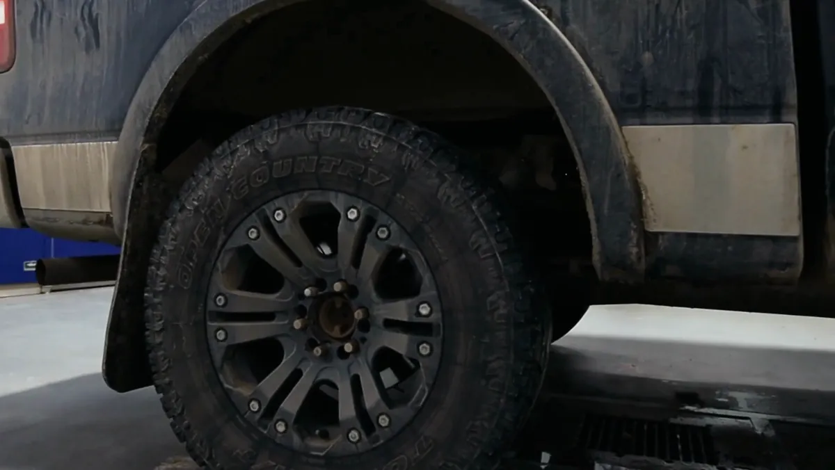 A mud-caked wheel and fender on a Ford F-150 before detailing