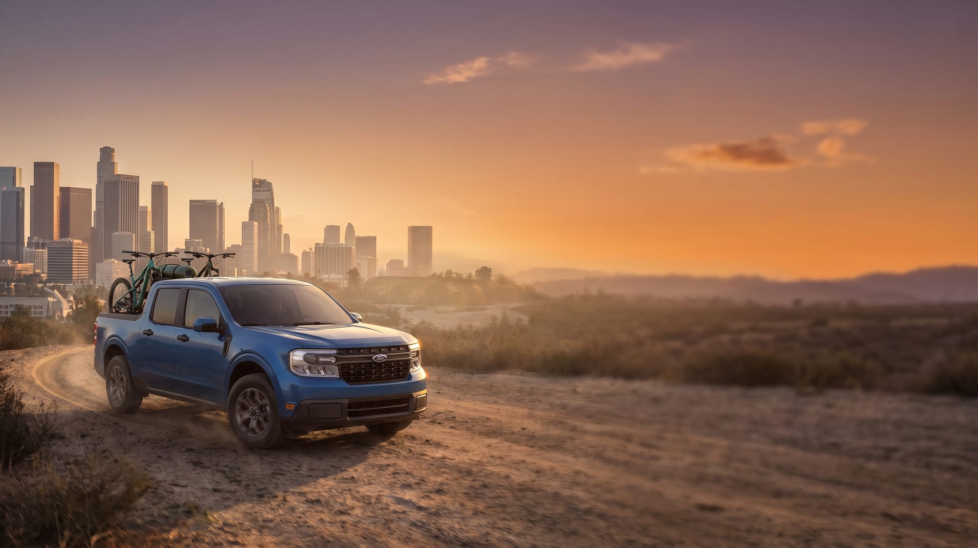 Ford Maverick with bikes in the bed, city skyline at sunset